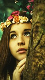 Close-up of young woman wearing tiara looking away while standing by tree