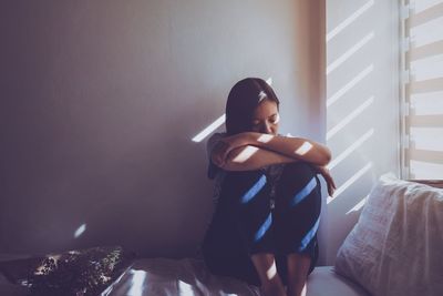 Woman sitting on bed at home