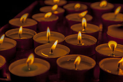 Close-up of burning tea light candles in darkroom