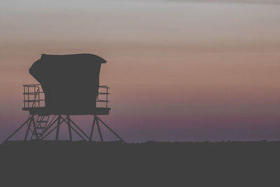 Silhouette water tower against sky during sunset