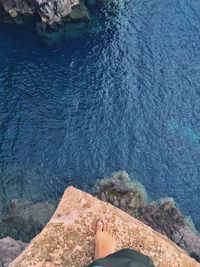 Low section of woman on rock by sea