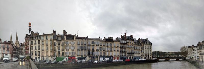 Panoramic view of buildings by river against sky