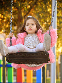 Close-up of girl sitting on swing at playground