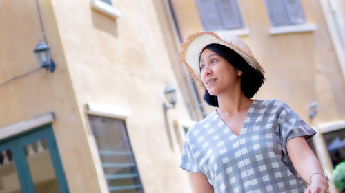 Portrait of beautiful young woman standing against building