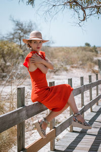 Woman wearing hat while sitting on railing