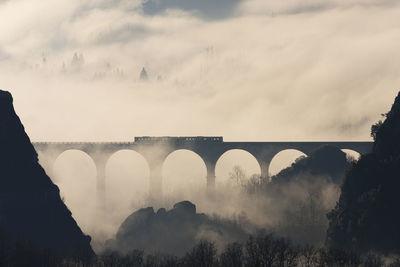 Panoramic shot of arch bridge against fog