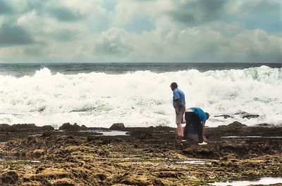 Rear view of man looking at sea against sky