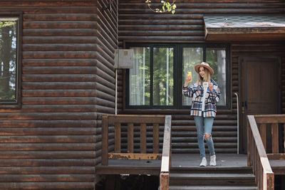 Full length of young woman standing against building