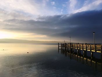 Pier on sea against sky at sunset