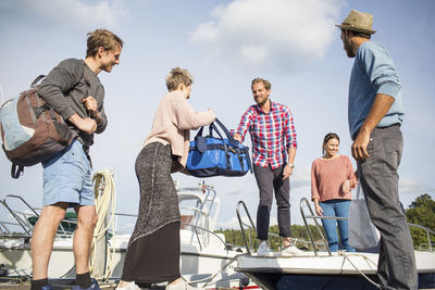 Woman handing bag to friend on yacht