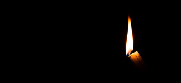 Close-up of lit candle in darkroom