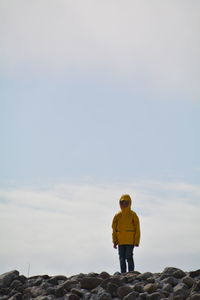 Child standing on stones against sky