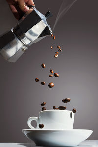 Cropped hand pouring coffee beans in cup on table