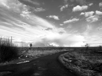 Road amidst field against sky