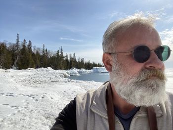 Portrait of man wearing sunglasses against sky during winter