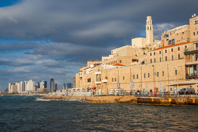Buildings by river against sky