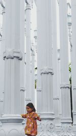 Girl standing amidst columns in city