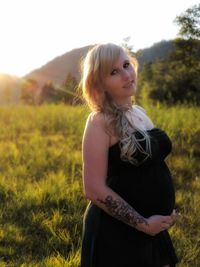 Portrait of pregnant woman standing on field