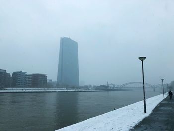 Sea by city against sky during winter