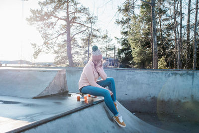 Woman sitting on her skateboard in a skatepark thinking in the sun