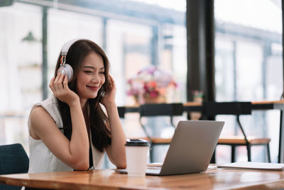 Young woman using phone while sitting on table