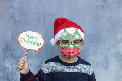 Portrait of boy wearing mask standing against wall