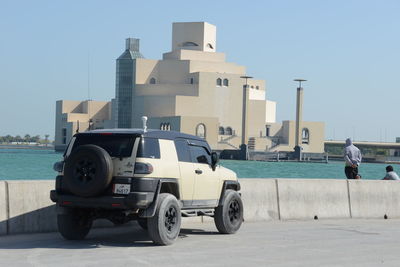 Cars on road by buildings against clear sky