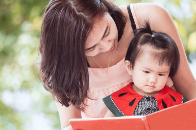 Woman with daughter against plants