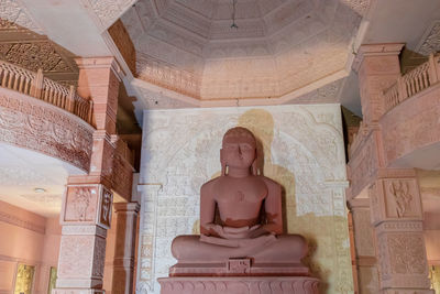 Isolated red stone jain god holy statue in meditation from different angle