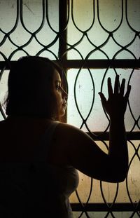 Rear view of woman looking through window