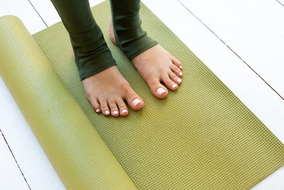 Womens beautiful feet in green leggings on rubber sports mat or fitness mat