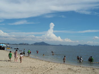 People enjoying at beach against sky