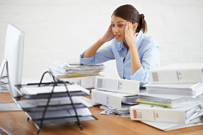 Frustrated businesswoman sitting with files at office