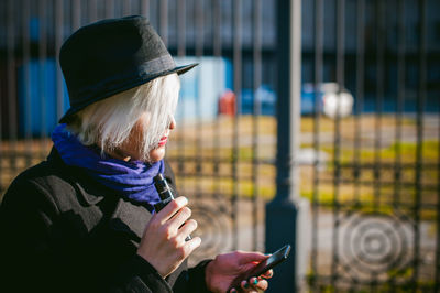 Young woman using mobile phone while smoking at park