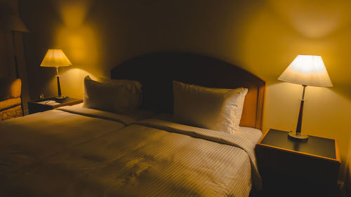 Illuminated electric lamp on bed at home