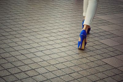 Low section of woman with high heels walking on footpath