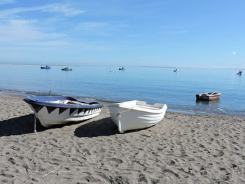 Boats moored on beach against sky