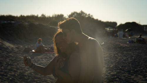 Side view of young woman looking away while standing at beach