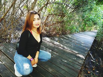 Portrait of beautiful young woman against tree