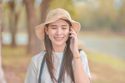 Portrait of smiling young woman standing against blurred background