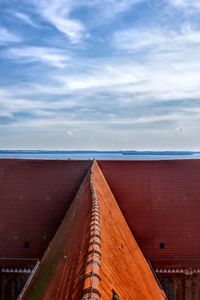 Wooden roof of building by sea against sky