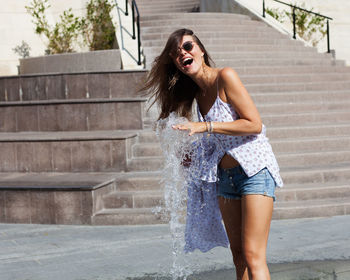 Happy woman playing with water by fountain