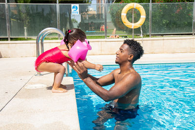 Rear view of woman holding water in swimming pool