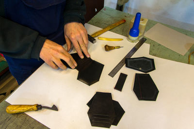 Midsection of shoemaker making shoe on table