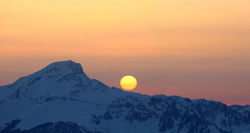 Scenic view of snowcapped mountains against sky during sunset