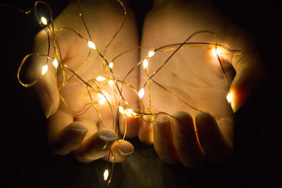 Close-up of human hands holding illuminated chain of lights 