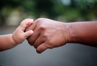 Cropped hand of baby touching father hand