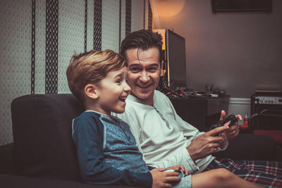 Smiling father and cute son playing video game at home