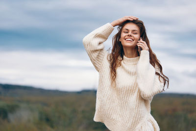 Young woman standing against sky