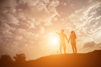 Silhouette people standing against sky during sunset